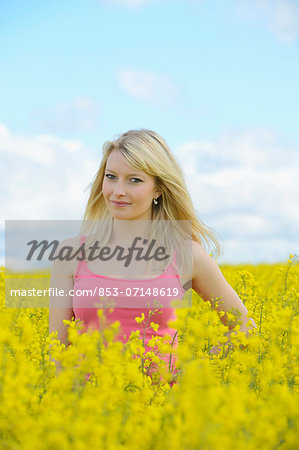 Blond young woman in blossoming rape field