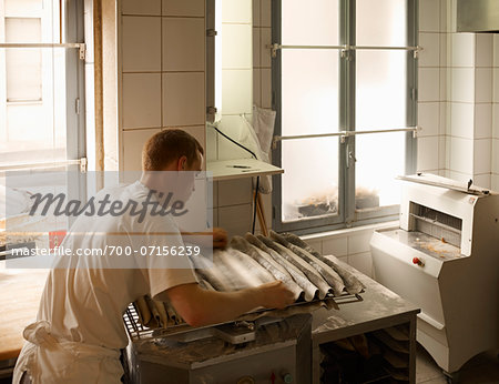 Male baker shaping baguette bread dough by hand in bakery, Le Boulanger des Invalides, Paris, France Male baker shaping baguette bread dough by hand in bakery, Le Boulanger des Invalides, Paris, France