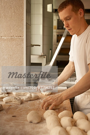 Male baker shaping bread dough by hand in bakery, Le Boulanger des Invalides, Paris, France