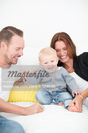 Happy parents playing with son on bed