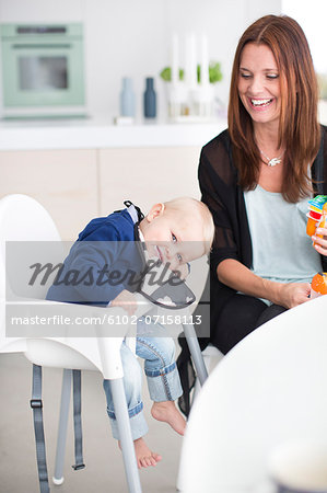 Smiling mother with son sitting in highchair