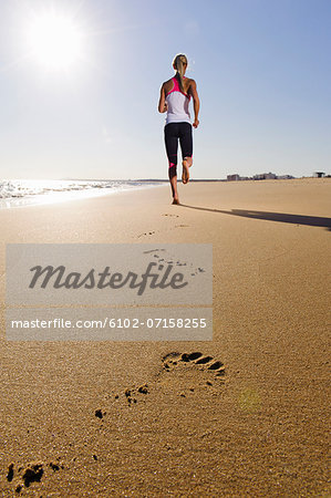 Young woman running on beach, Algarve, Portugal