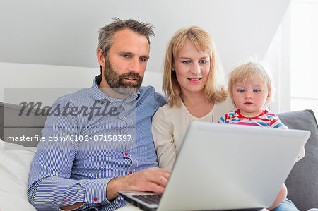 Parents with daughter using laptop