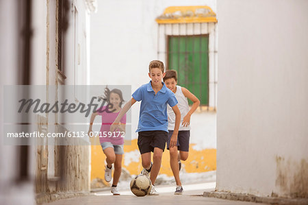 Children playing with soccer ball in alley