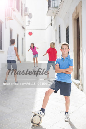 Boy holding soccer ball in alley