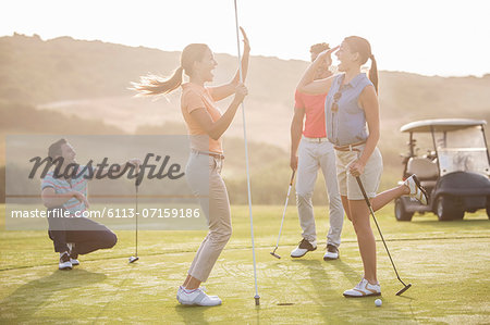 Women high fiving on golf course