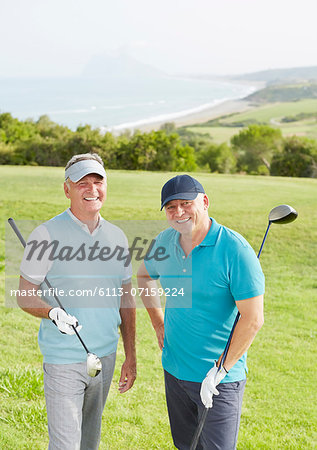 Senior men smiling on golf course overlooking ocean