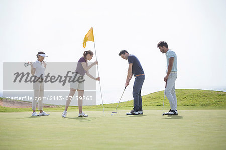 Friends putting on golf course