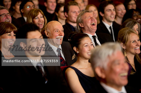 People smiling and laughing in theater audience