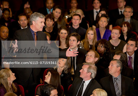 Theater audience watching standing man gesturing