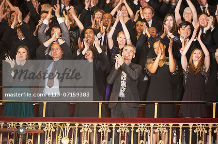 Enthusiastic audience clapping in theater balcony