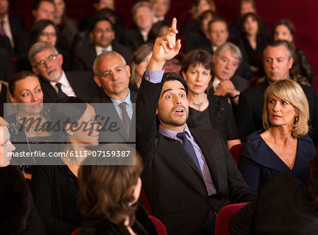 Man raising hand in theater audience