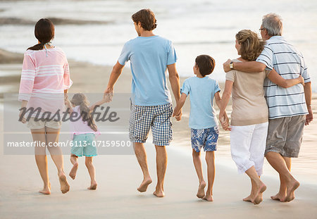 Multi-generation family holding hands on beach