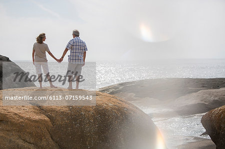 Senior couple holding hands on rocks at beach