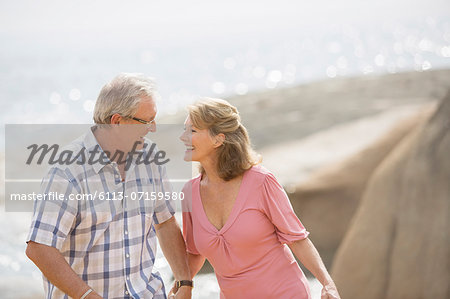 Older couple holding hands on beach