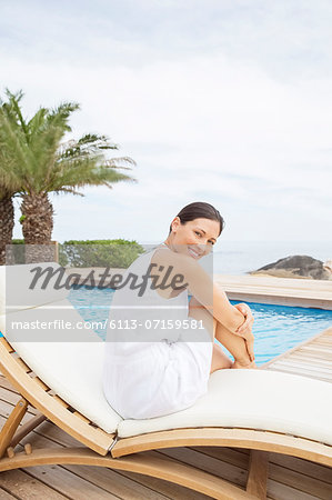 Woman relaxing in lawn chair by pool