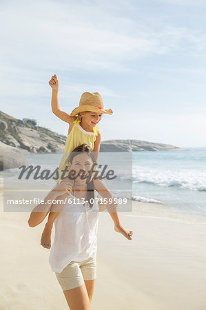 Mother carrying daughter on shoulders on beach Mother carrying daughter on shoulders on beach