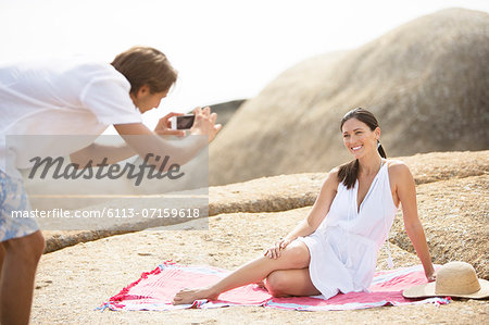 Man taking picture of girlfriend on beach