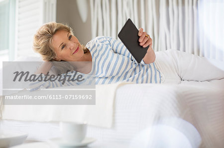 Older woman using digital tablet on bed