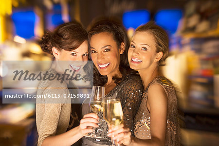 Smiling women toasting champagne glasses in nightclub