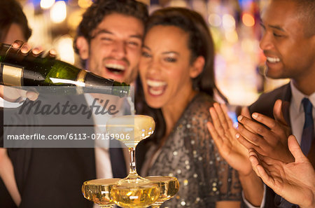 Close up of laughing couple pouring champagne pyramid