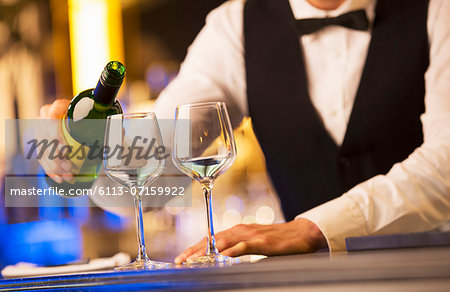 Well dressed bartender pouring wine