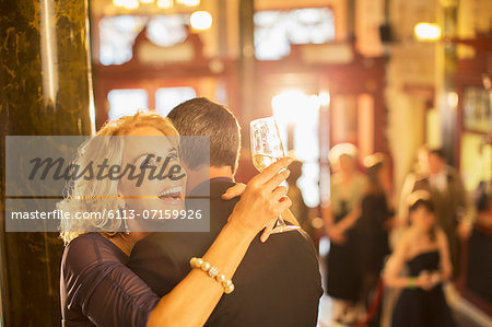 Enthusiastic woman with champagne hugging man in theater lobby Enthusiastic woman with champagne hugging man in theater lobby