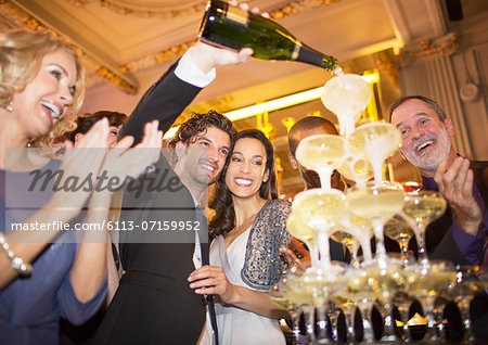 Well dressed couple pouring champagne pyramid