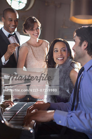 Well dressed friends playing piano in luxury nightclub