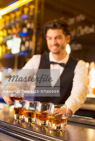 Well dressed bartender pouring bourbon in luxury bar