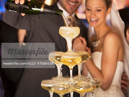 Groom pouring champagne pyramid at wedding reception
