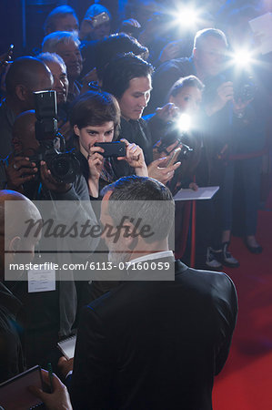 Well dressed male celebrity signing autographs at red carpet event