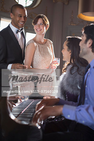 Well dressed friends playing piano in lounge Well dressed friends playing piano in lounge