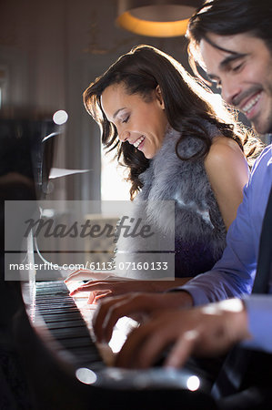 Close up of well dressed couple playing piano