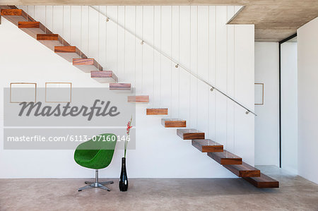 Chair under floating staircase in modern house