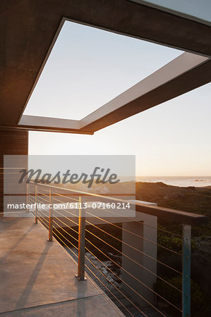 Balcony of modern house overlooking ocean at sunset