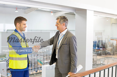 Supervisor and worker shaking hands in factory