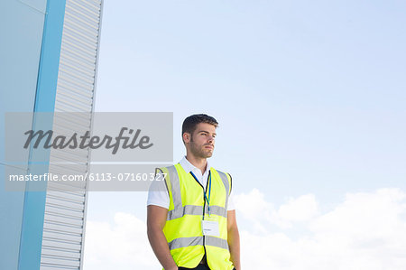 Worker standing below highrise building