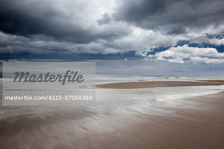 Clouds over beach at low tide