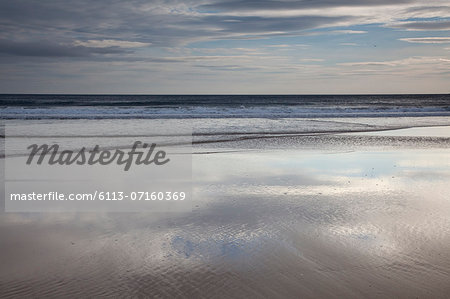 Sun reflecting on beach at low tide