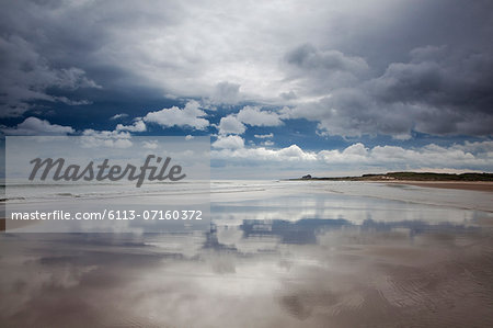 Reflection of clouds on beach at low tide