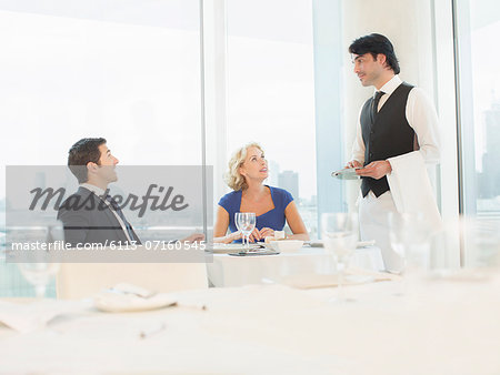 Business people talking to waiter in restaurant