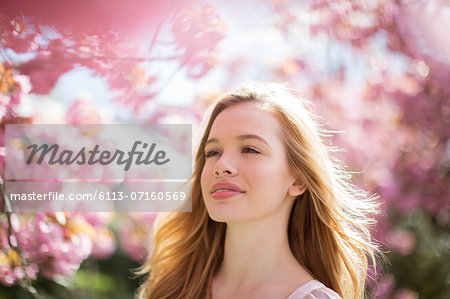 Woman walking under tree with pink blossoms