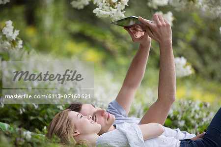 Couple taking self-portrait with digital tablet in park