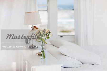 Vase of flowers and lamp in white bedroom