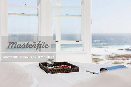 Breakfast tray and magazine on bed overlooking ocean