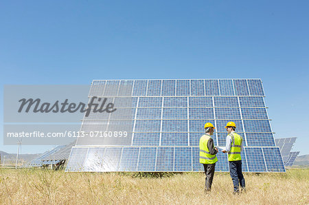 Workers examining solar panel in rural landscape