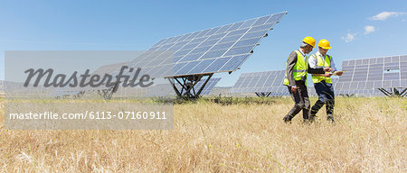 Workers walking by solar panels in rural landscape