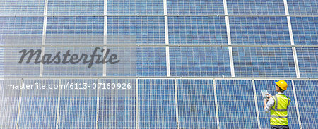 Worker examining solar panel in rural landscape