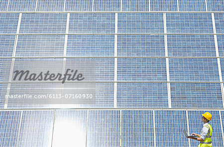 Worker examining solar panel in rural landscape